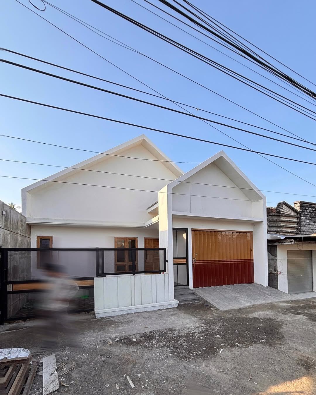Fanji House - tampak depan double gable putih dengan rolling door dua warna kuning + maroon